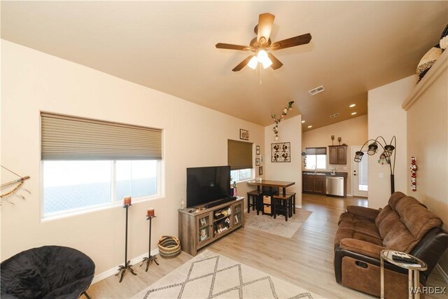 living area featuring lofted ceiling, a healthy amount of sunlight, visible vents, and light wood-style floors