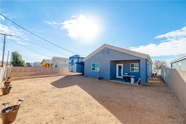 rear view of property featuring a fenced backyard and stucco siding