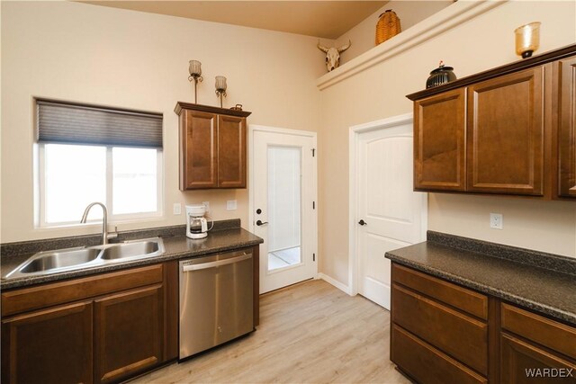 kitchen featuring a sink, dark countertops, light wood finished floors, and stainless steel dishwasher