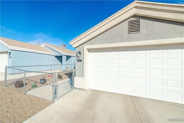 garage featuring driveway, fence, and a gate