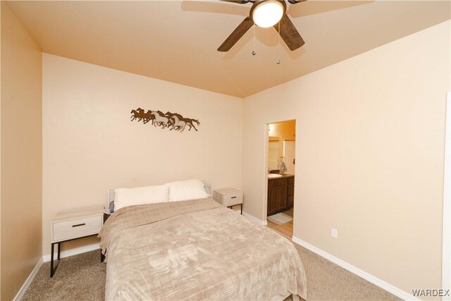 bedroom featuring light carpet, ensuite bathroom, a ceiling fan, and baseboards