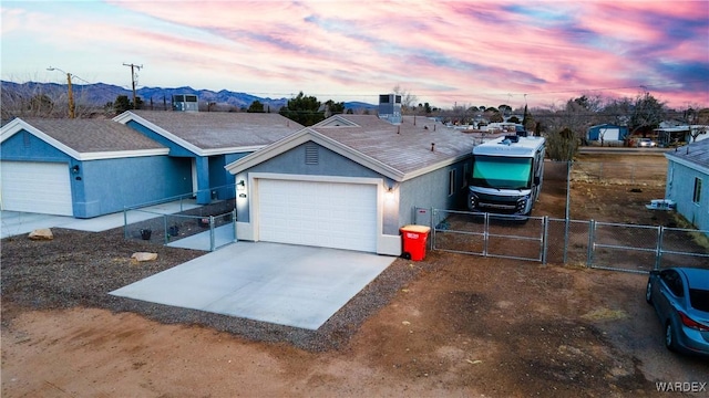 ranch-style house with a mountain view, fence, driveway, a gate, and stucco siding