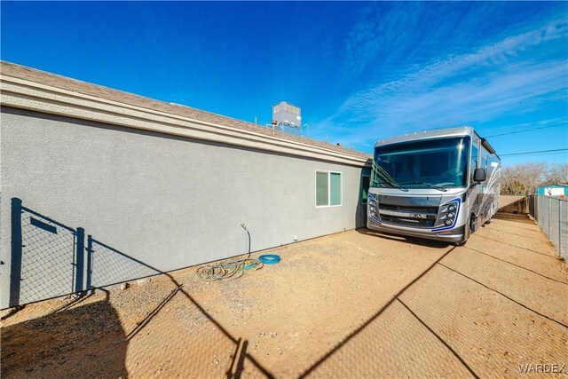 view of side of home featuring fence and stucco siding