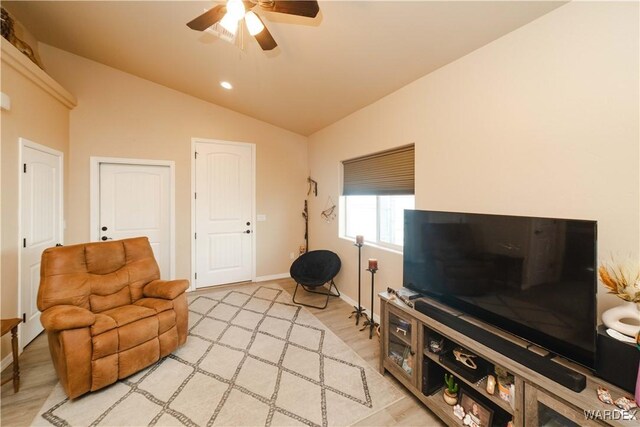 living area with vaulted ceiling, light wood finished floors, a ceiling fan, and baseboards