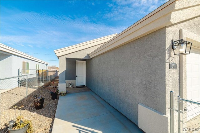 view of exterior entry featuring a patio, fence, and stucco siding