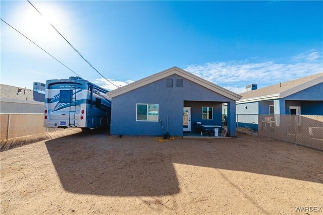 rear view of property with fence and stucco siding