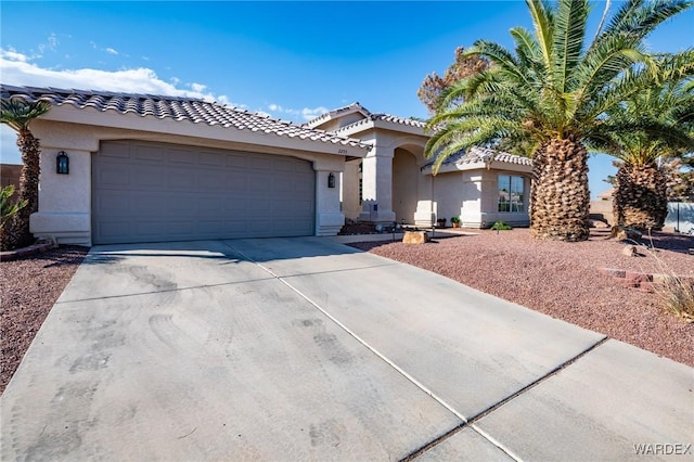 mediterranean / spanish home with a garage, driveway, a tile roof, and stucco siding