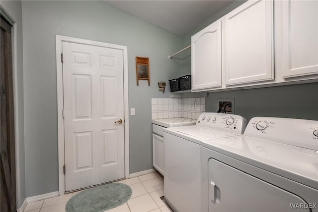 laundry area with cabinet space, baseboards, separate washer and dryer, and light tile patterned flooring