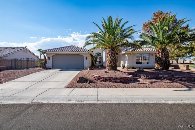 view of front of property with concrete driveway, a tiled roof, an attached garage, fence, and stucco siding