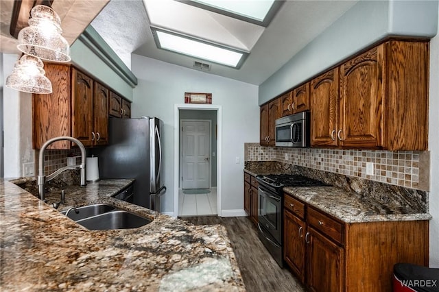 kitchen with stainless steel appliances, lofted ceiling, visible vents, and dark stone counters