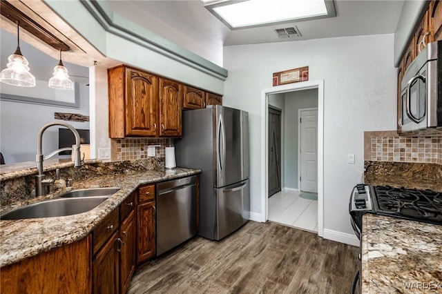 kitchen with a sink, visible vents, appliances with stainless steel finishes, dark wood-style floors, and decorative light fixtures