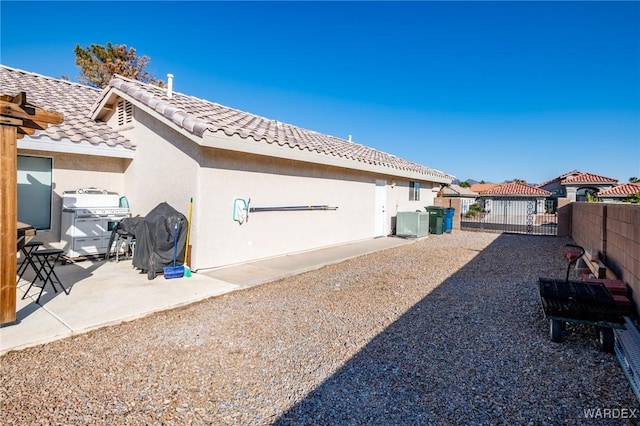 rear view of property featuring a tile roof, central air condition unit, stucco siding, a gate, and fence