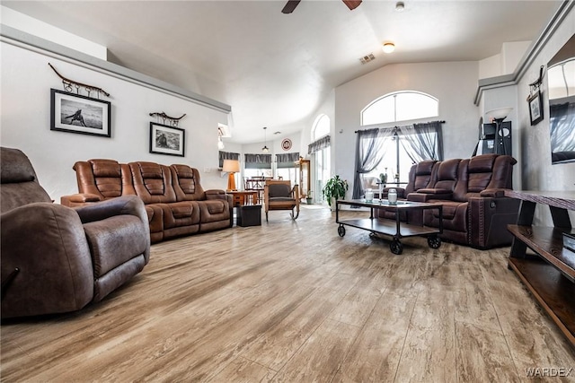 living area with lofted ceiling, visible vents, light wood-style flooring, and a ceiling fan