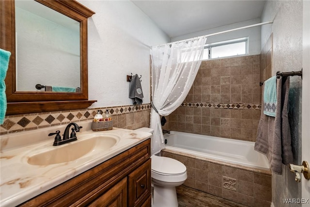 full bathroom with toilet, tiled shower / bath combo, vanity, and tile walls