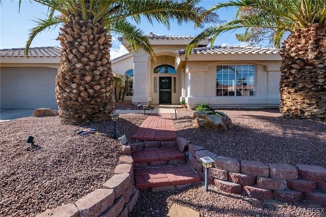 view of front of home with a garage, a tile roof, and stucco siding