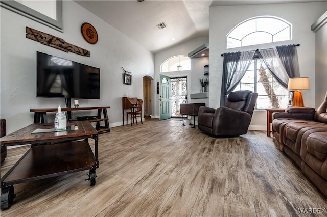 living room featuring arched walkways, wood finished floors, visible vents, and baseboards