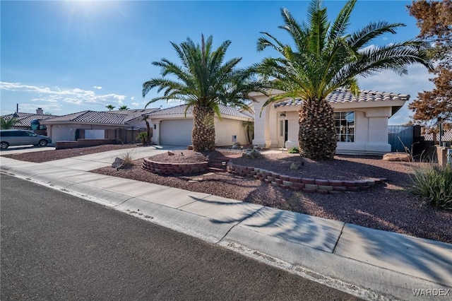 view of front of home featuring concrete driveway, a tile roof, an attached garage, and stucco siding