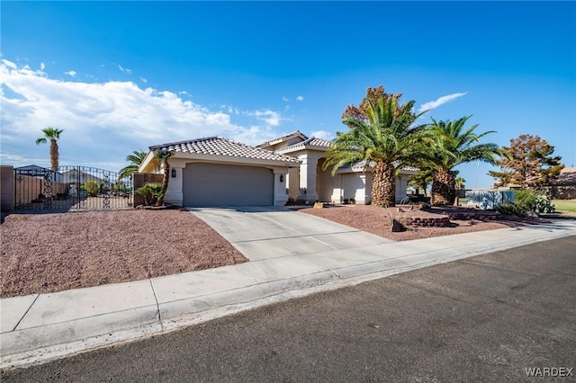 mediterranean / spanish-style home with a garage, concrete driveway, a tiled roof, a gate, and stucco siding