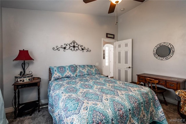 bedroom featuring arched walkways, vaulted ceiling, dark carpet, and baseboards