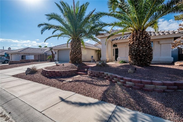 view of front of property with concrete driveway, an attached garage, a tile roof, and stucco siding