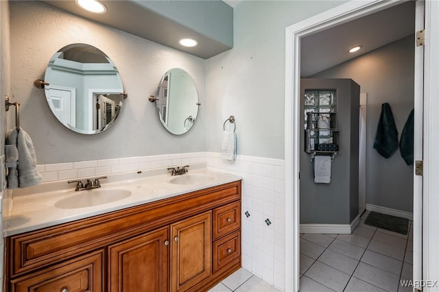 full bathroom with double vanity, a sink, tile walls, and tile patterned floors