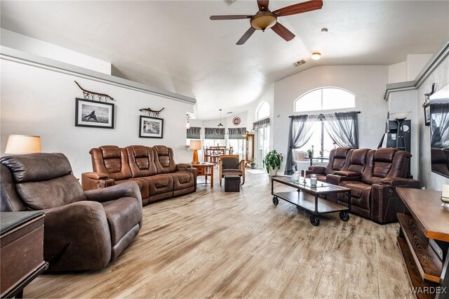 living room featuring ceiling fan, light wood-style flooring, and vaulted ceiling