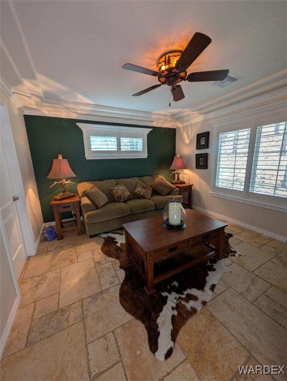 living area with baseboards, ornamental molding, visible vents, and stone tile floors