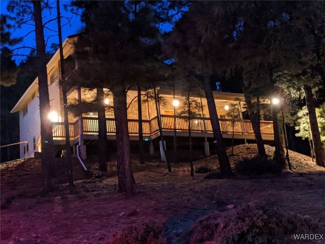 back of house at night featuring a deck