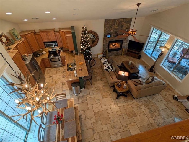 living room with washer / dryer, ceiling fan, stone finish flooring, a fireplace, and recessed lighting