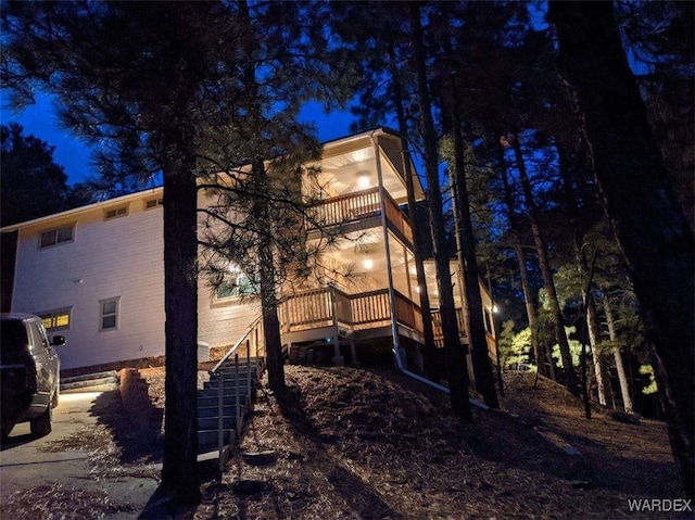 property exterior at night featuring stairway and a balcony