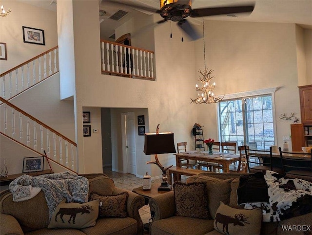 living room featuring stairs, ceiling fan with notable chandelier, a towering ceiling, and visible vents