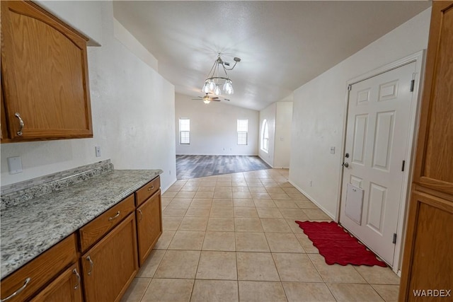 2970 E Devlin Ave, Kingman, AZ 86409 - interior space featuring brown cabinetry, lofted ceiling, light tile patterned flooring, open floor plan, and hanging light fixtures