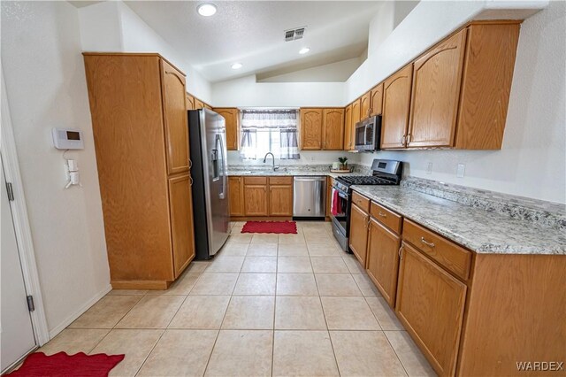2970 E Devlin Ave, Kingman, AZ 86409 - kitchen featuring a sink, brown cabinetry, stainless steel appliances, vaulted ceiling, and visible vents