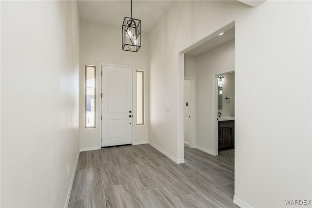 entryway featuring light wood finished floors, a high ceiling, and baseboards