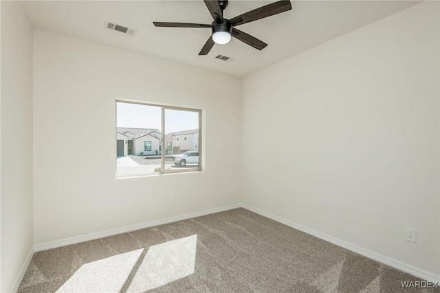 carpeted spare room with baseboards, visible vents, and a ceiling fan