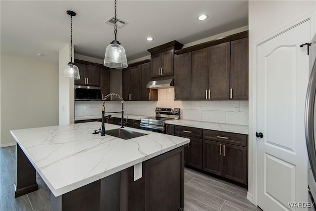 kitchen with hanging light fixtures, appliances with stainless steel finishes, a sink, an island with sink, and under cabinet range hood