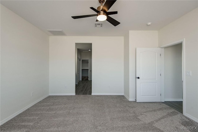 unfurnished bedroom featuring baseboards, visible vents, dark colored carpet, and a ceiling fan