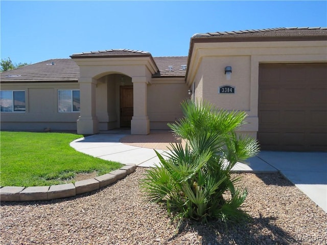 view of front of house featuring a front yard, a tiled roof, an attached garage, and stucco siding