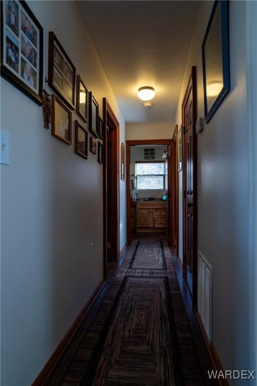 hallway with baseboards and visible vents