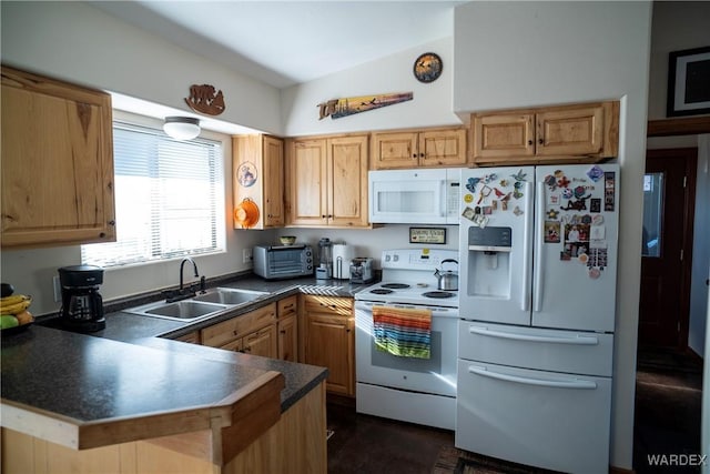 kitchen featuring a toaster, dark countertops, a sink, white appliances, and a peninsula