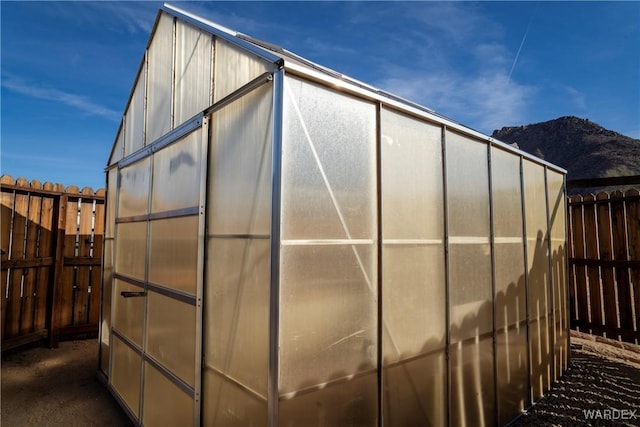 view of greenhouse featuring fence and a mountain view