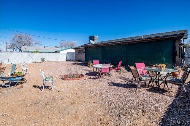 view of yard with cooling unit, fence, and outdoor dining space