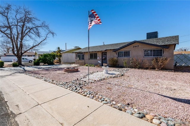 single story home with a fire pit, fence, and stucco siding