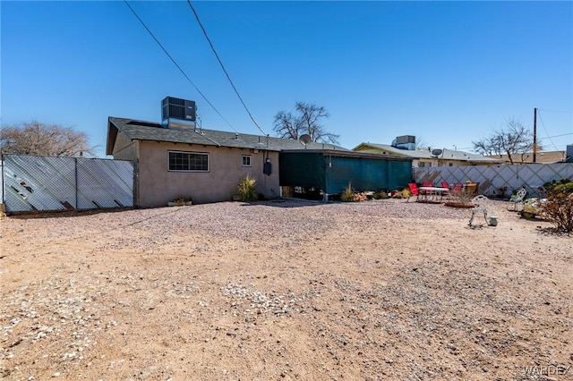 rear view of property featuring central AC, fence, and stucco siding