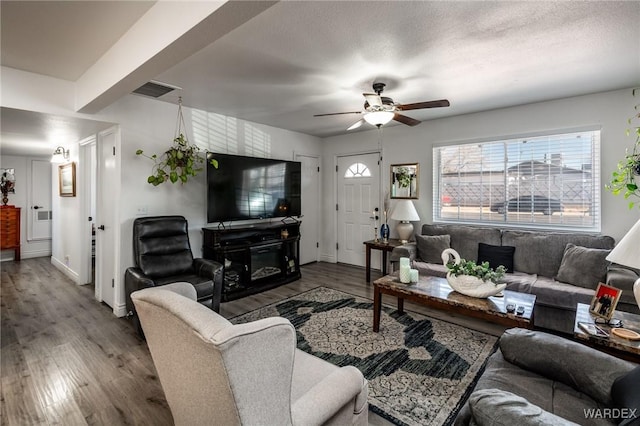 living room with visible vents, ceiling fan, a textured ceiling, and wood finished floors