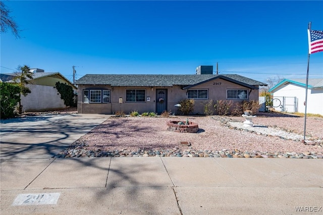 ranch-style home with an outdoor fire pit, fence, and stucco siding