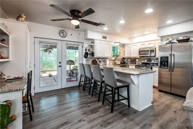 kitchen with stainless steel appliances, dark stone countertops, open shelves, and white cabinets