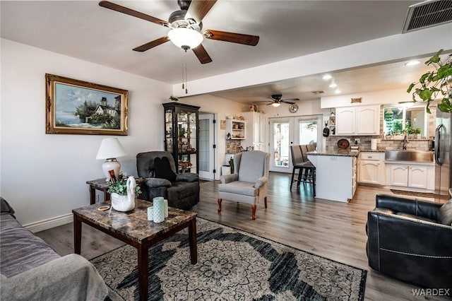 living room featuring light wood finished floors, baseboards, visible vents, and french doors