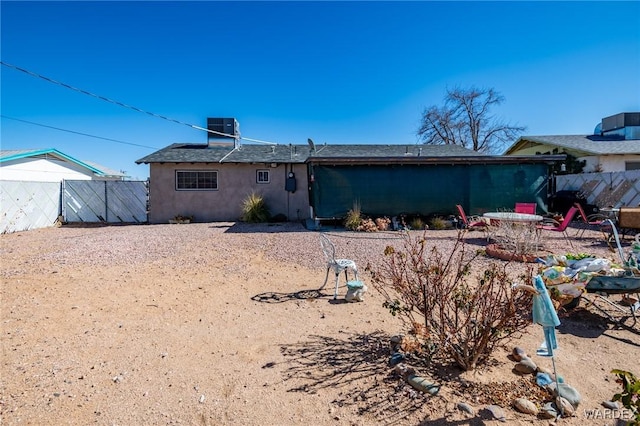 back of house featuring stucco siding, fence, and central air condition unit