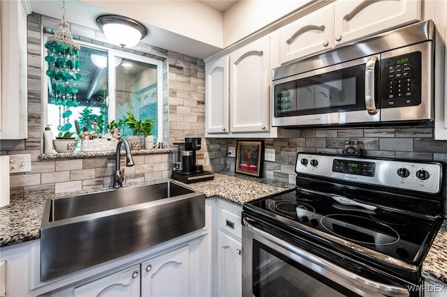 kitchen featuring appliances with stainless steel finishes, a sink, white cabinetry, and decorative backsplash